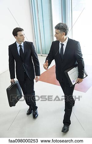 Businessmen passing through office building lobby together View Large Photo Image Stock Image - Businessmen passing through office building lobby together. Fotosearch