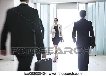 Picture - Businesswoman hurrying through office building lobby. Fotosearch