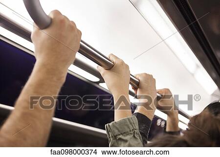 Picture - Communters on subway holding grab handle, close-up. Fotosearch