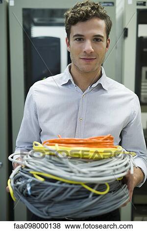 Stock Photo - Computer technician carrying coils of networking cables into server room. Fotosearch