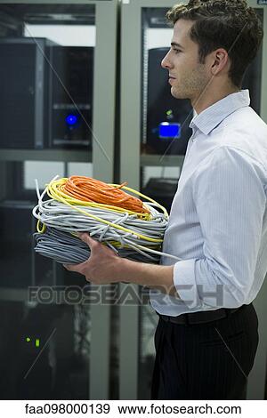 Stock Photo - Computer technician carrying coils of networking cables into server room. Fotosearch