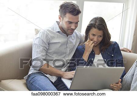 Couple using laptop computer together at home View Large Photo Image Stock Photo - Couple using laptop computer together at home. Fotosearch
