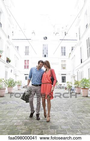 Couple walking together in building courtyard View Large Photo Image Stock Image - Couple walking together in building courtyard. Fotosearch