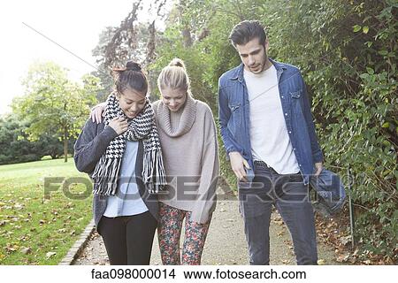 Picture - Friends strolling together in park. Fotosearch