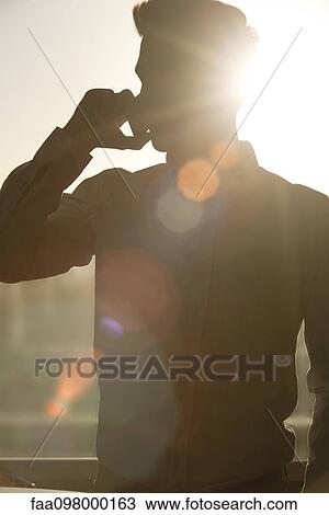 Man talking on cell phone, silhouetted by sun shining through window View Large Photo Image Stock Image - Man talking on cell phone, silhouetted by sun shining through window. Fotosearch