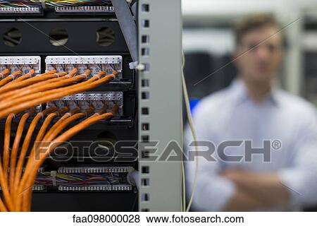 Network cables connected to computer mainframe, computer technician in background View Large Photo Image Stock Photo - Network cables connected to computer mainframe, computer technician in background. Fotosearch