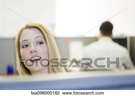Stock Image - Office worker peering over cubicle wall. Fotosearch
