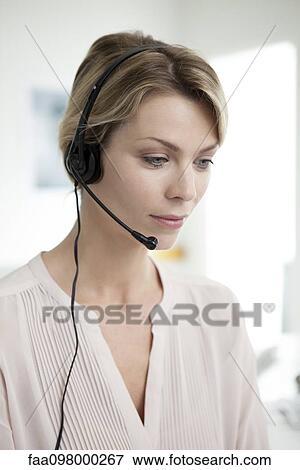 Stock Photo - Office worker wearing phone headset multitasking. Fotosearch
