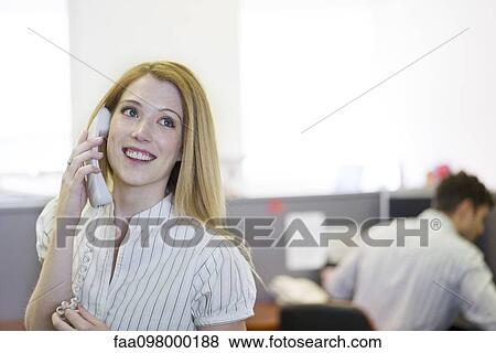 Stock Photo - Temp worker answering telephone in office. Fotosearch