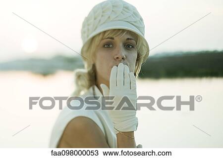 Stock Image - Woman blowing kisses with gloved hand. Fotosearch