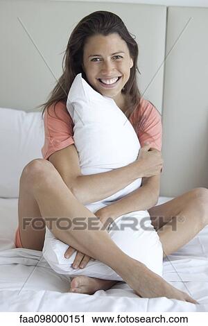 Stock Image - Woman enjoying softness of pillow. Fotosearch
