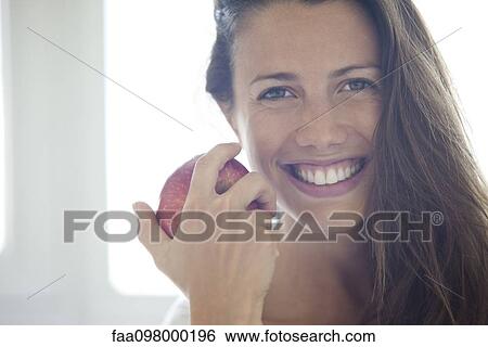 Stock Photograph - Woman holding apple, portrait. Fotosearch