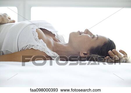Woman lying on bed, looking up and smiling dreamily View Large Photo Image Stock Image - Woman lying on bed, looking up and smiling dreamily. Fotosearch