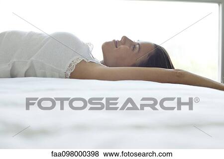 Woman lying on bed, looking up and smiling dreamily View Large Photo Image Stock Photo - Woman lying on bed, looking up and smiling dreamily. Fotosearch