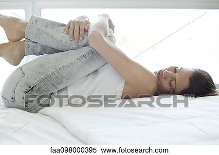 Woman lying on bed with knees against chest View Large Photo Image Stock Photography - Woman lying on bed with knees against chest. Fotosearch
