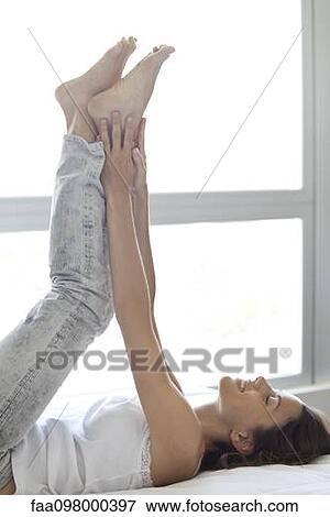 Woman lying on bed with legs raised in the air View Large Photo Image Stock Photo - Woman lying on bed with legs raised in the air. Fotosearch
