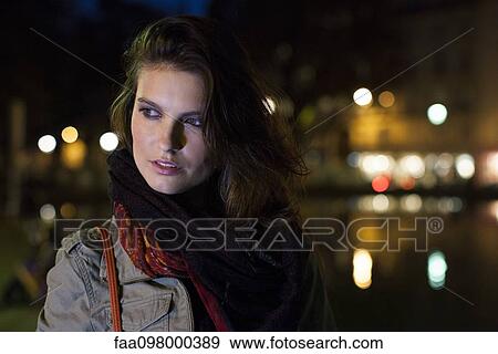 Stock Photo - Woman outdoors at night, portrait. Fotosearch