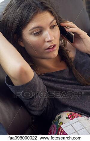 Woman reclining on sofa talking on cell phone View Large Photo Image Stock Image - Woman reclining on sofa talking on cell phone. Fotosearch