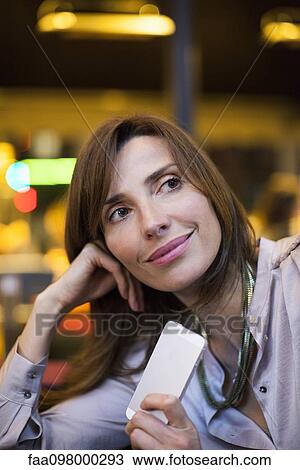 Stock Image - Woman satisfied with good news received on smartphone while on the move. Fotosearch