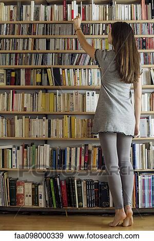 Stock Photo - Woman selecting book from shelf, rear view. Fotosearch