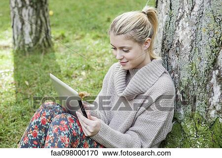Stock Image - Woman using digital tablet in park. Fotosearch
