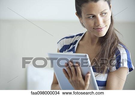 Picture - Woman using digital tablet, smiling over shoulder. Fotosearch