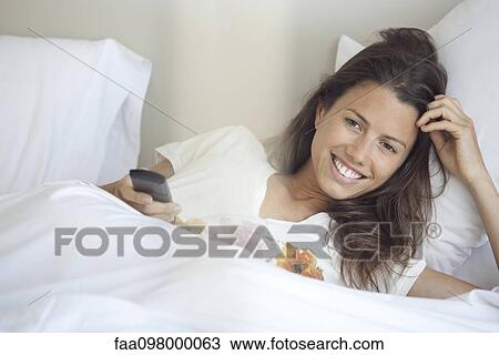 Stock Image - Woman watching TV in bed. Fotosearch