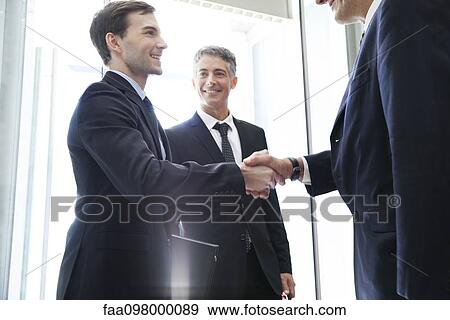 Young businessman shaking hands with senior associate View Large Photo Image Stock Photo - Young businessman shaking hands with senior associate. Fotosearch
