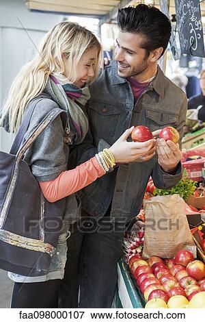 Stock Photo - Young couple at greengrocer's shopping for fresh fruits and vegetables. Fotosearch