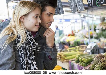Stock Photograph - Young couple at greengrocer's shopping for fresh fruits and vegetables. Fotosearch