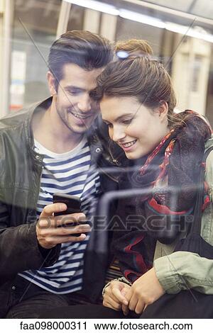 Young couple riding subway looking at digital tablet together View Large Photo Image Stock Image - Young couple riding subway looking at digital tablet together. Fotosearch