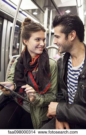 Picture - Young couple riding subway together. Fotosearch