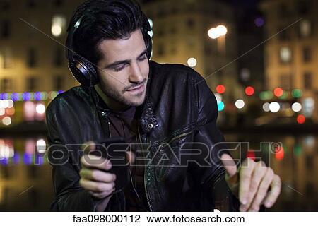 Stock Image - Young man listening to music with headphones. Fotosearch