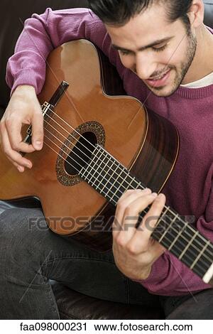 Stock Image - Young man playing acoustic guitar. Fotosearch