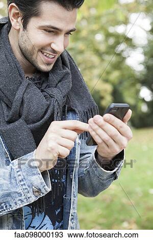 Young man using smartphone outdoors View Large Photo Image Stock Image - Young man using smartphone outdoors. Fotosearch