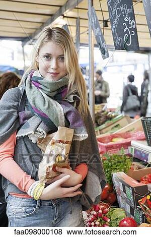 Stock Photo - Young woman at greengrocer's buying fresh fruits and vegetables. Fotosearch