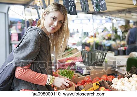 Stock Image - Young woman at greengrocer's shopping for fresh fruits and vegetables. Fotosearch