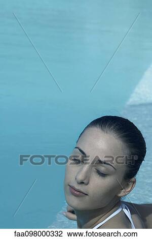 Stock Image - Young woman in swimming pool, eyes closed. Fotosearch