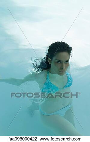 Stock Image - Young woman in swimming pool, portrait. Fotosearch