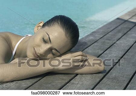 Young woman leaning on poolside, eyes closed View Large Photo Image Stock Photo - Young woman leaning on poolside, eyes closed. Fotosearch