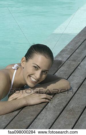 Young woman leaning on poolside, smiling View Large Photo Image Picture - Young woman leaning on poolside, smiling. Fotosearch