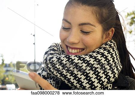 Young woman looking at smartphone View Large Photo Image Stock Photo - Young woman looking at smartphone. Fotosearch