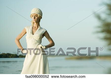 Stock Image - Young woman modeling dress and hat outdoors. Fotosearch