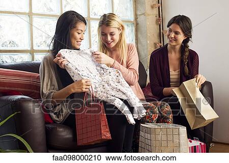 Young woman showing friends contents of shopping bag View Large Photo Image Stock Image - Young woman showing friends contents of shopping bag. Fotosearch