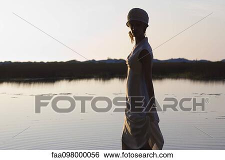 Young woman wearing dress in front of lake at dusk View Large Photo Image Stock Photograph - Young woman wearing dress in front of lake at dusk. Fotosearch