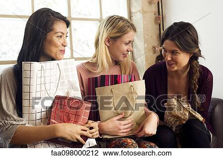 Young women chatting together with shopping bags on their laps View Large Photo Image Stock Image - Young women chatting together with shopping bags on their laps. Fotosearch