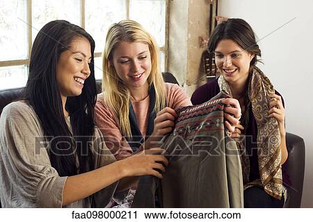 Stock Image - Young women looking at clothing together. Fotosearch
