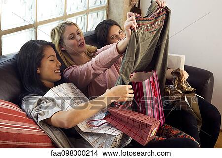 Young women looking at contents of shopping bags together View Large Photo Image Picture - Young women looking at contents of shopping bags together. Fotosearch
