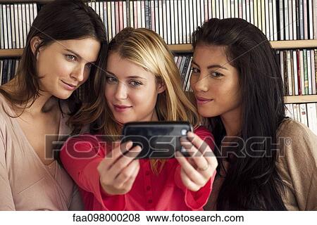 Stock Photo - Young women posing together for selfie. Fotosearch