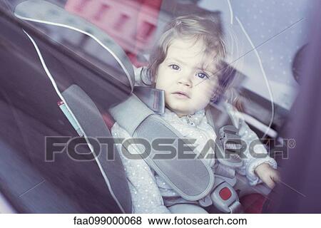 Stock Photo - Baby girl sitting in car seat, gazing through car window. Fotosearch